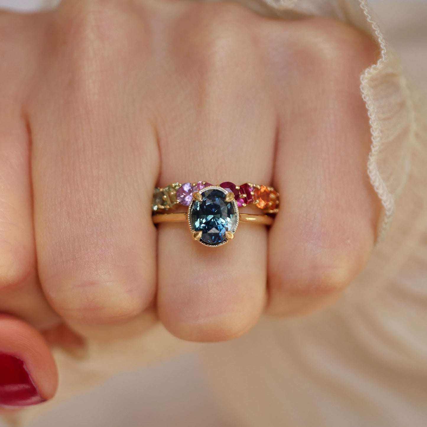 A stunning blue sapphire engagement ring with a vintage-inspired design, paired with a complementary rainbow wedding band for a perfect and unique bridal set.