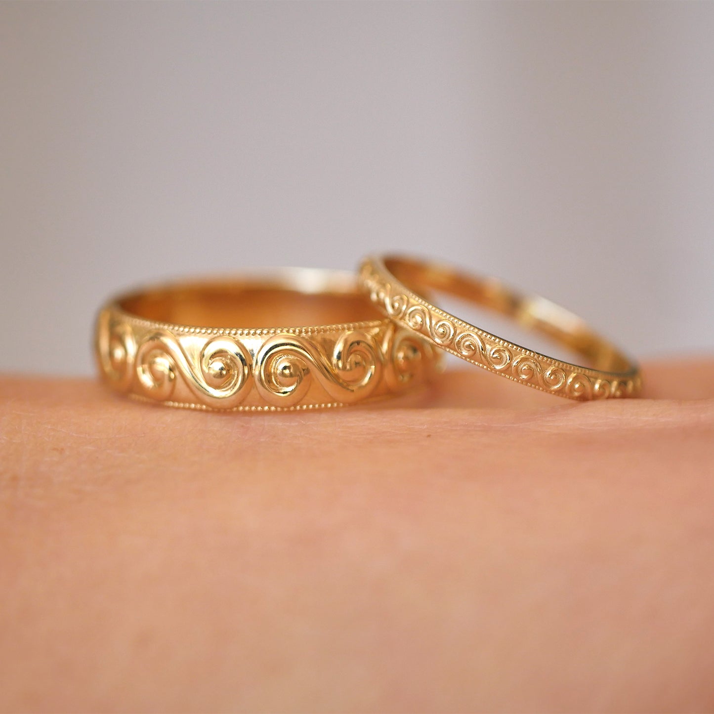 Two 14k yellow gold wide and delicate spiral and wind engraved wedding bands.