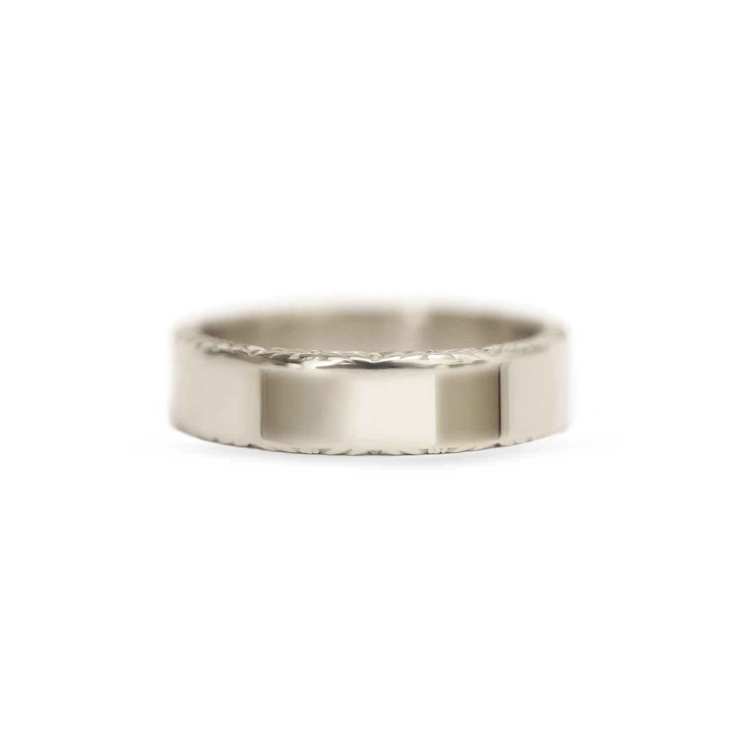 A man's wedding band with floral engraving set in 14k white gold.