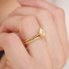Woman wearing yellow lozenge diamond engagement ring with floral-engraved wedding band.