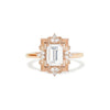 A rose gold ring featuring a colorless emerald cut Moissanite center stone with natural round brilliant diamonds around it.