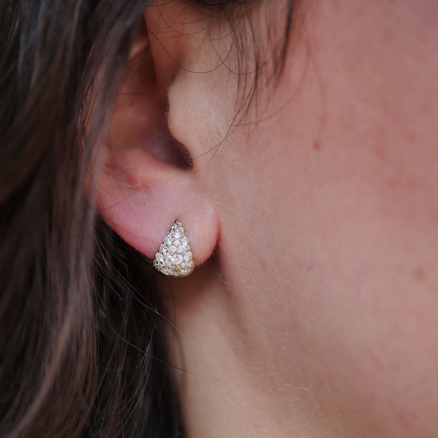 Close-up of an ear wearing a cobblestone huggie diamond earrings.