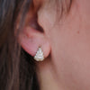 Close-up of a person wearing a teardrop-shaped diamond earring with huggie closure.