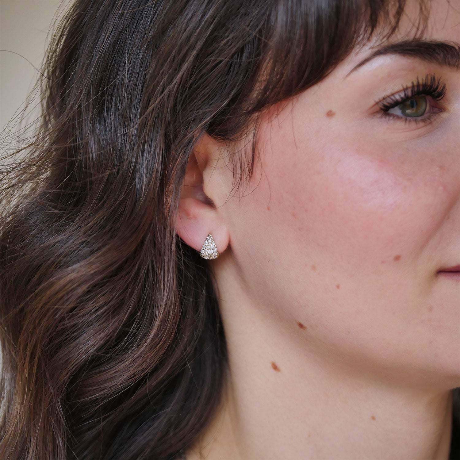 Close-up of a woman wearing cobblestone diamond earrings.