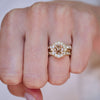 Gold ring with diamond on a person's finger against a neutral background