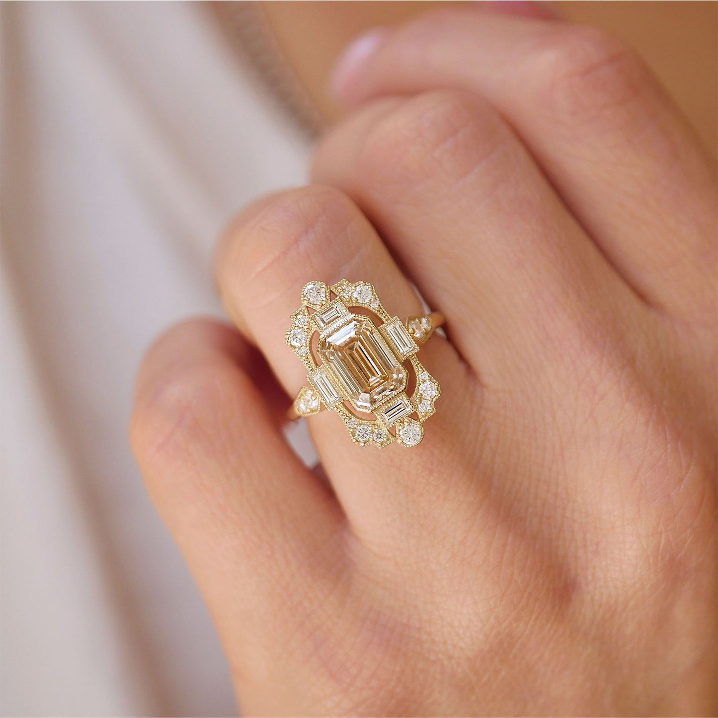 woman showing unique and art deco details of an engagement ring with champagne center diamond and diamond mosaic ring