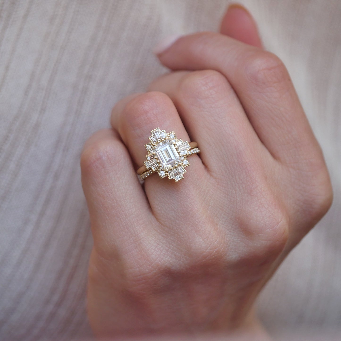 woman wearing 14k yellow gold deco moissanite and diamond engagement ring stacked with diamond pave band