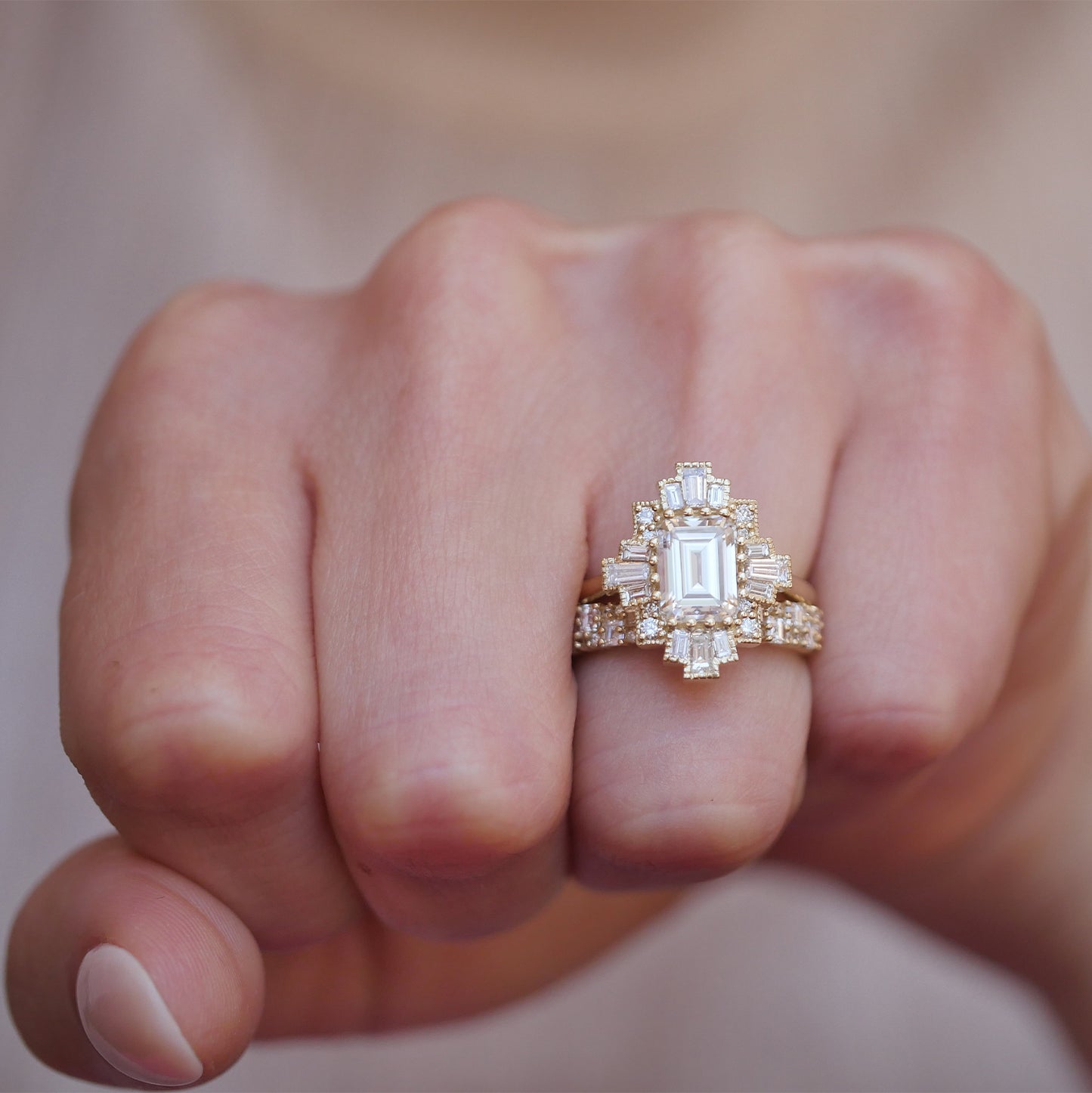 woman wearing unique 14k yellow gold deco moissanite and diamond engagement ring paired with the deco brick diamond band