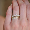 Hand wearing a diamond mosaic engagement ring, stacked with a star engraved and pave diamond band