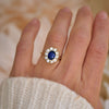 Woman wearing a blue sapphire and old european diamond cluster rings.