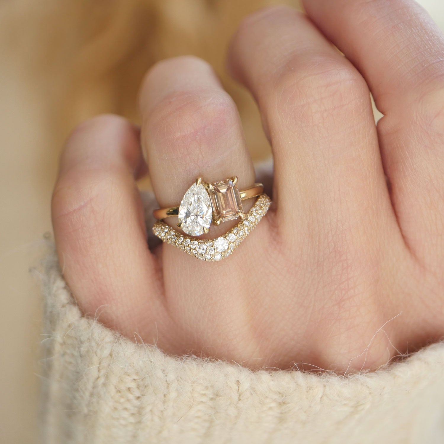 The rich, golden tones of the champagne emerald diamond contrast beautifully with the brilliance of the pear diamond, making this toi et moi ring a stunning symbol of love’s complexity and unity. Stacked with diamond contour wedding band.