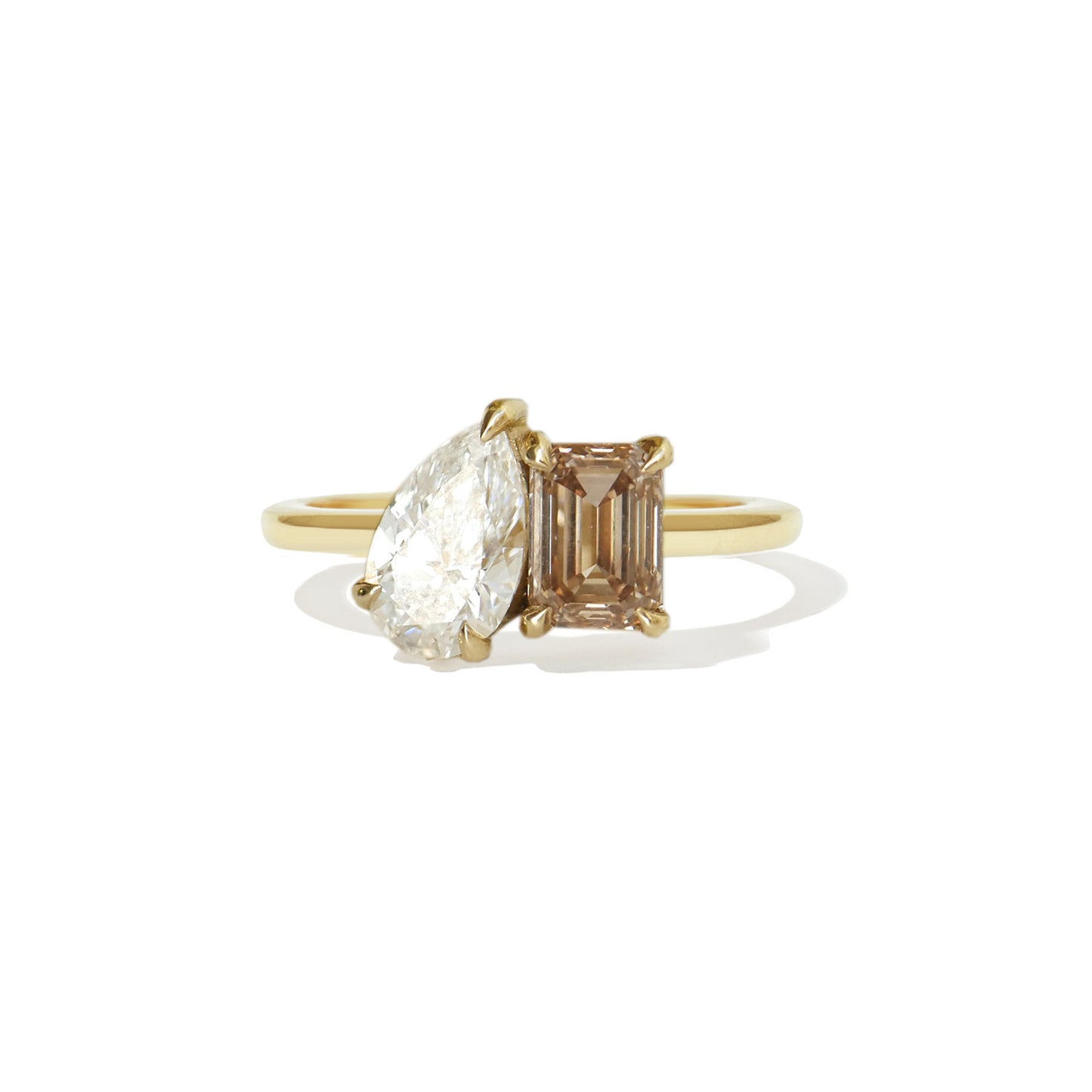 This toi et moi ring features a captivating pear-shaped diamond alongside a rich champagne emerald diamond, creating a unique and luxurious blend of elegance and warmth.