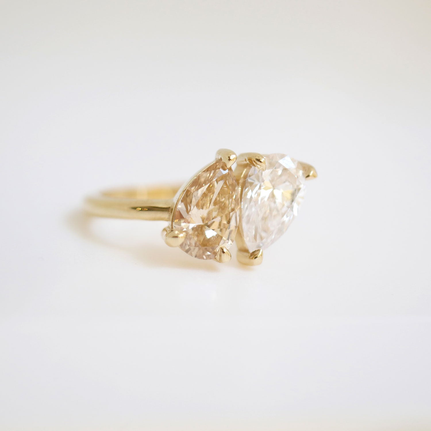 The soft, golden hue of the pear-shaped champagne diamond adds a touch of sophistication, making this ring a unique and timeless expression of love and devotion.