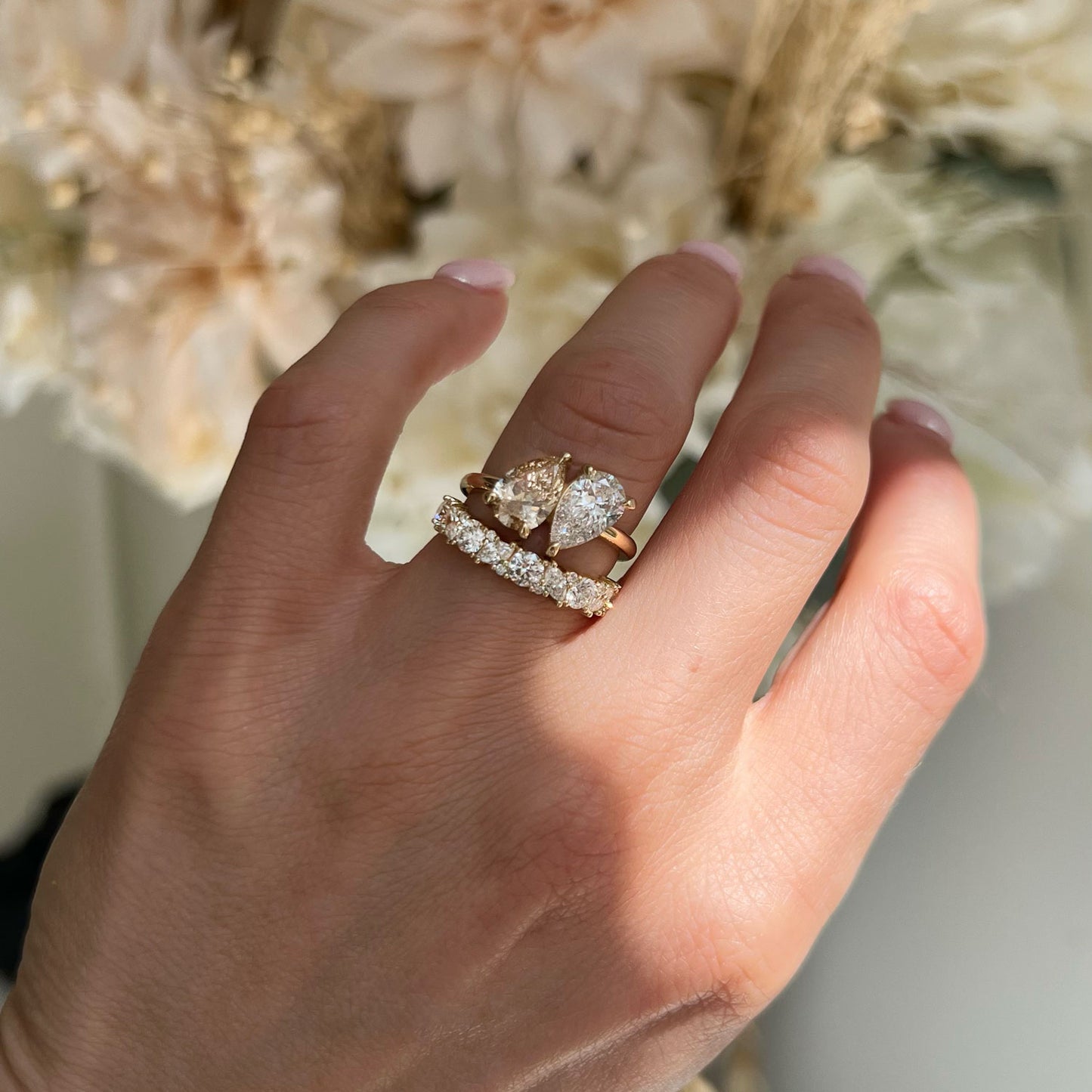 The graceful pear shape of the champagne diamond is designed to capture light from every angle, making it a radiant and unforgettable centerpiece in this toi et moi ring. Stacked with diamond wedding band.
