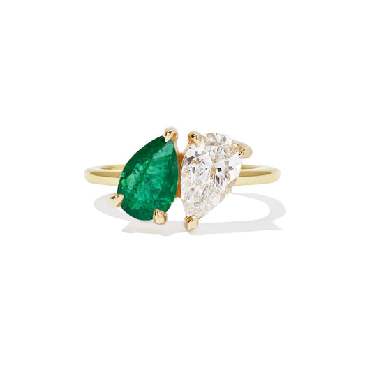 This ring features a stunning pear-shaped emerald paired with a sparkling diamond, creating a striking combination of rich color and timeless elegance.