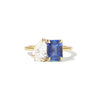 The ring elegantly combines a deep blue sapphire, a radiant green emerald, and a sparkling pear-shaped diamond, creating a truly unique and vibrant design.